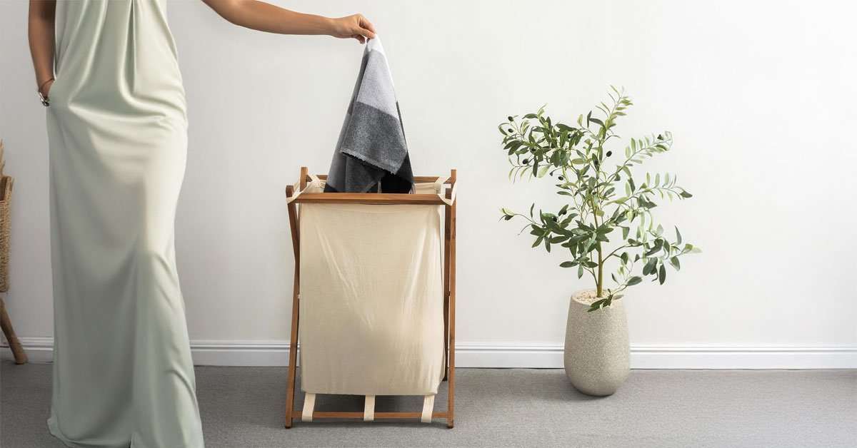 Acacia wood folding laundry hamper with cotton-linen liner in a bedroom setting