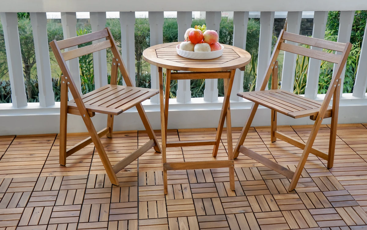acacia wood patio bistro set arranged on a small balcony