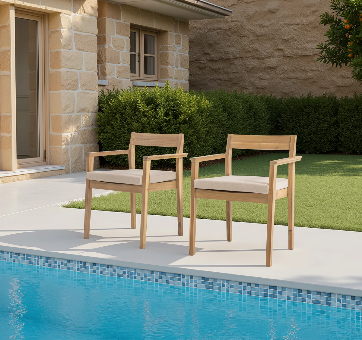 Two acacia wood patio chairs with cream cushions by a swimming pool